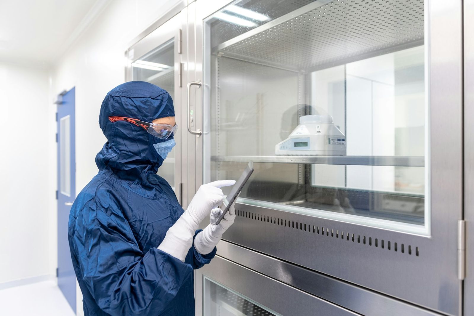 Technician in protective clothing checking equipment in a clean room
